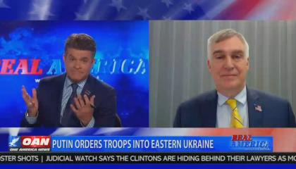 OAN host Dan Ball expressively shrugging mid-sentence. Chyron reads "Putin orders troops into eastern Ukraine" 